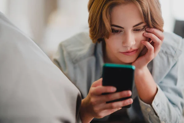 Portret van jonge vrouw met smartphone, liggend op de bank thuis, sociaal netwerk concept. — Stockfoto