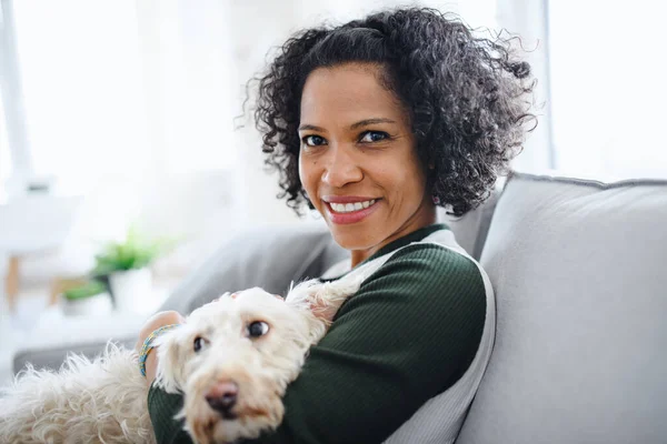 Retrato de mujer madura feliz con perro sentado en casa, mirando a la cámara. —  Fotos de Stock