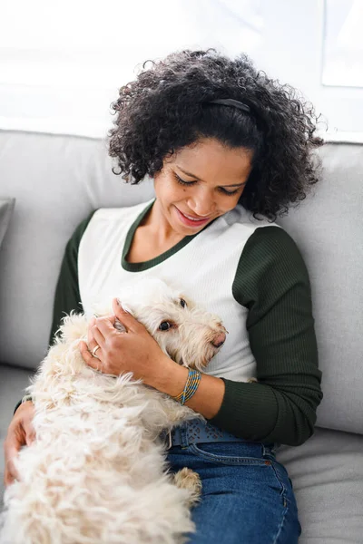 Portret van gelukkig volwassen vrouw zitten binnen, spelen met hond. — Stockfoto