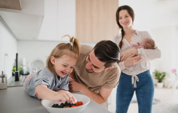 Joyeux jeune famille avec bébé nouveau-né et petite fille profiter du temps ensemble à la maison, concept de routine quotidienne. — Photo