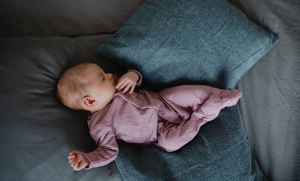 Top view of newborn baby girl, sleeping an lying on sofa indoors at home. — Stock Photo, Image