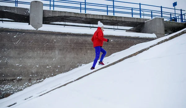Widok z boku aktywnej starszej kobiety biegnącej po schodach na zewnątrz w śnieżnej zimie. — Zdjęcie stockowe