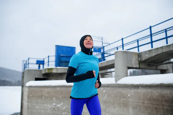 Actieve senior vrouw loopt buiten in besneeuwde winter, koud weer concept. — Stockfoto