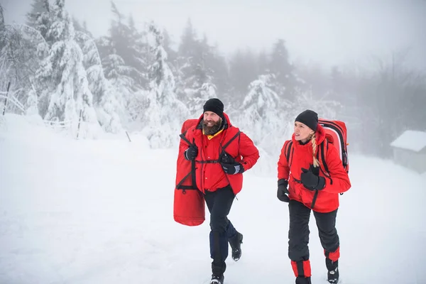 Sjukvårdare från fjällräddningstjänsten springer utomhus på vintern i skogen. — Stockfoto