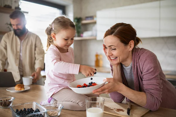 Family with small daughter indoors in kitchen at home, everyday life and home office with child concept. — Stock Photo, Image