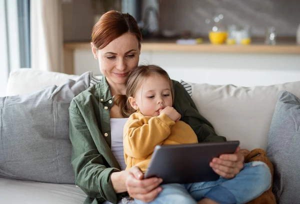 Madre feliz con hija pequeña viendo el programa de niños en la tableta en el interior de casa, concepto de paternidad soltera. — Foto de Stock