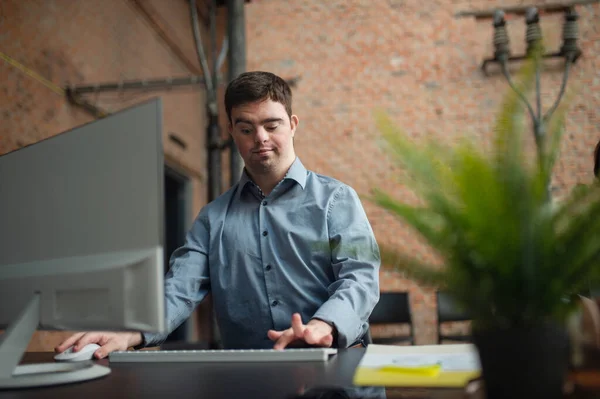 Vrolijke jonge Down Syndroom zakenman werken aan het bureau, sociale inclusie concept. — Stockfoto