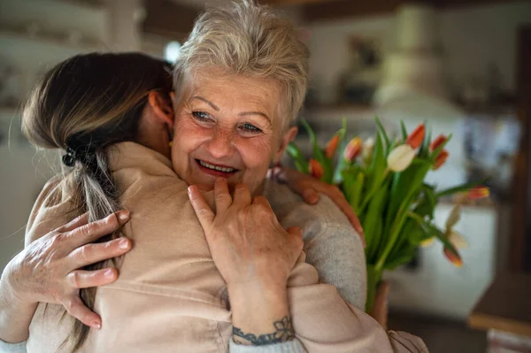 Glückliche ältere Mutter umarmt erwachsene Tochter zu Hause, Muttertag oder Geburtstagsfeier. — Stockfoto