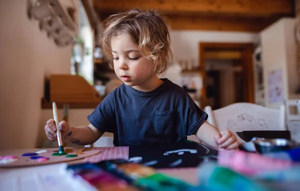 Концентрированная маленькая девочка рисует картины в помещении дома, досуг. — стоковое фото