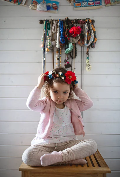 Ritratto di bambina con corona di fiori popolari seduta in casa — Foto Stock