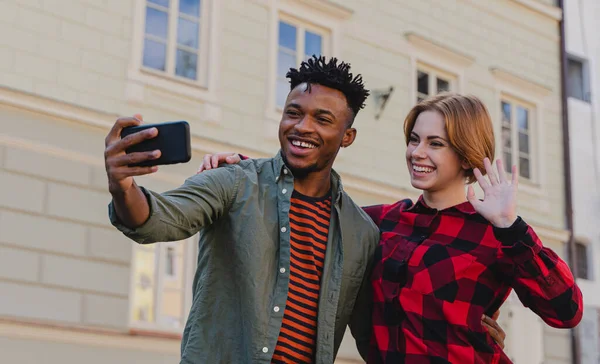 Young mixed couple making selfie for soial networks outdoors in town. — Stock Photo, Image