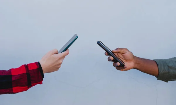 Gros plan de jeunes mains mixtes en utilisant des smartphones sur fond blanc — Photo