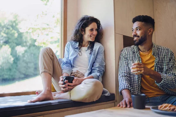 幸せなカップルは、木の家、週末、デジタルデトックスのコンセプトで屋内で座って休憩してコーヒーを飲む. — ストック写真