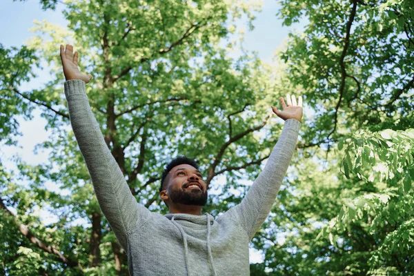Vista a basso angolo di felice giovane uomo che fa esercizio di stretching all'aperto nella foresta, fine settimana e concetto di disintossicazione digitale. — Foto Stock