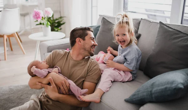 Anak muda yang bahagia merawat bayinya yang baru lahir dan anak kecilnya di dalam rumah, cuti ayah. — Stok Foto