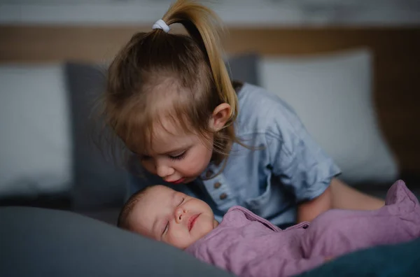 Menina beijando sua irmã bebê recém-nascido em casa no sofá. — Fotografia de Stock