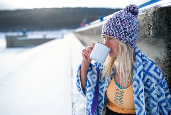 Ritratto di donna anziana attiva vestiti sportivi bere tè all'aperto in inverno, concetto di terapia fredda. Copia spazio. — Foto Stock