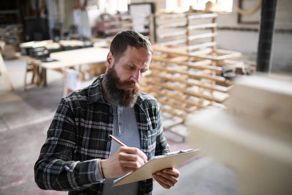 Retrato de carpinteiro masculino maduro esboçando design de seu produto dentro de casa na oficina de carpintaria. Conceito de pequenas empresas. — Fotografia de Stock