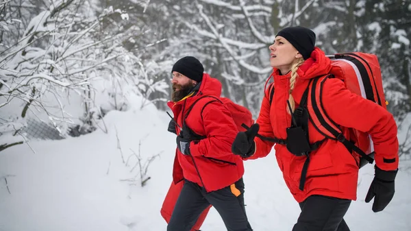 Sanitäter der Bergwacht laufen im Winter im Wald im Freien. — Stockfoto