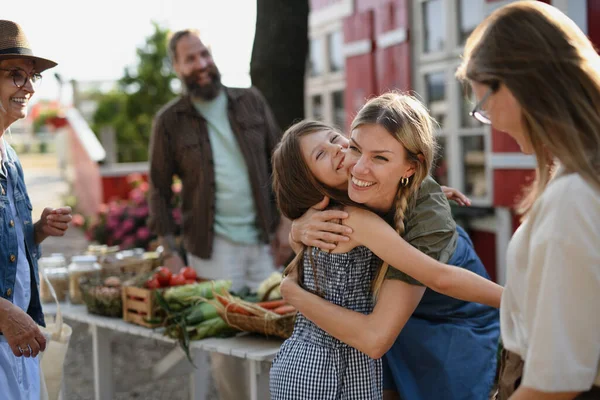 Niña con madre abrazándose al aire libre en el mercado de agricultores comunitarios. —  Fotos de Stock