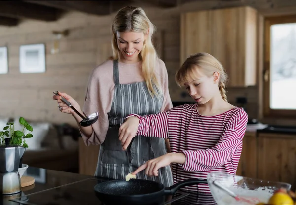 집안에서 요리를 하고 있는 어린 딸 이 있는 어머니, 개인 아파트에서의 겨울 휴가. — 스톡 사진