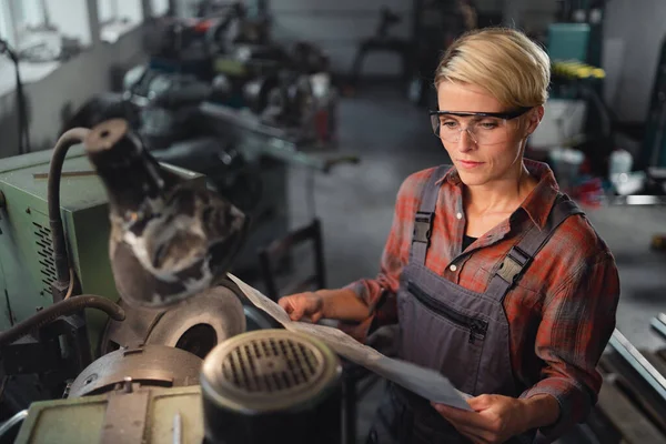 Vista de ángulo alto de la mujer industrial adulta media que trabaja en interiores en taller de metal. — Foto de Stock