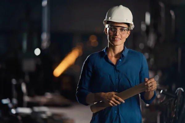 Portret van midden volwassen industriële vrouw die binnen werkt in een metaalwerkplaats, kijkend naar de camera. — Stockfoto