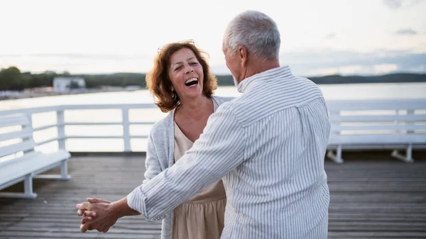 Felice coppia di anziani che balla all'aperto sul molo via mare, guardandosi l'un l'altro. — Foto Stock