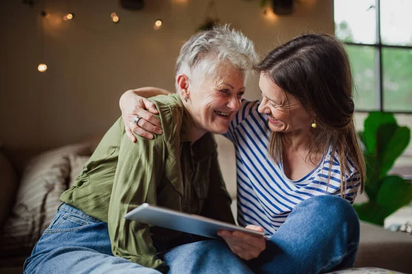 Porträt einer glücklichen Seniorin mit erwachsener Tochter zu Hause mit Tablet. — Stockfoto