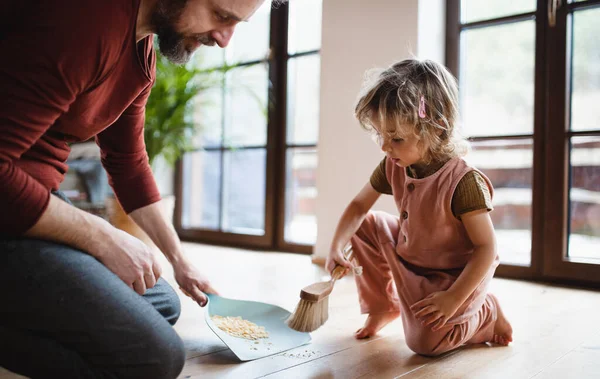 Pertengahan ayah dewasa dengan putri kecil menyapu cornflakes di rumah, konsep pekerjaan sehari-hari. — Stok Foto