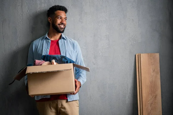 Happy young man holding packing boxes moving home, copy space. New living concept. — Stock Photo, Image