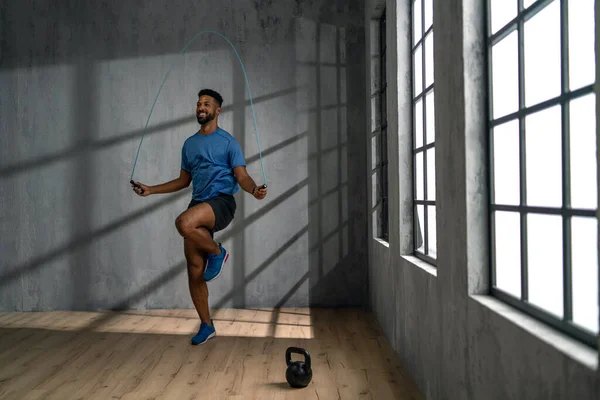 Pemuda Afrika Amerika olahragawan menggunakan melompat tali di dalam ruangan, latihan konsep pelatihan. — Stok Foto