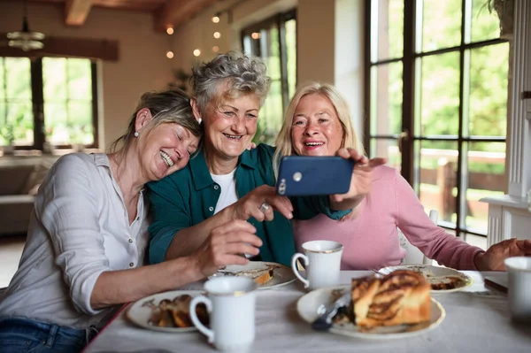 Glückliche Senioren bei Kaffee und Kuchen und Selfie zu Hause. — Stockfoto