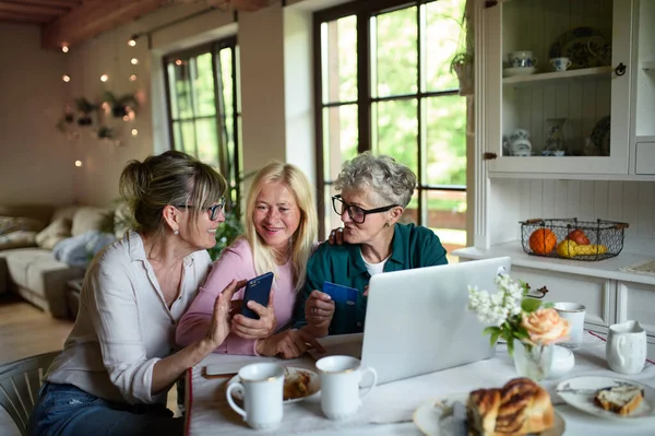 Happy senior friends using laptop and smartphone indoors at home, coffee time. — Stock Photo, Image