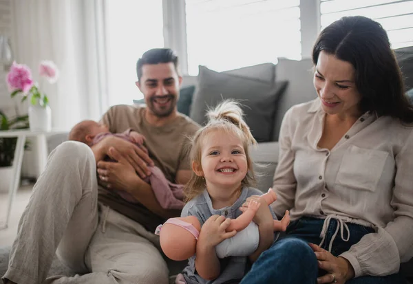 Feliz familia joven con bebé recién nacido y niña disfrutando del tiempo juntos en casa. —  Fotos de Stock