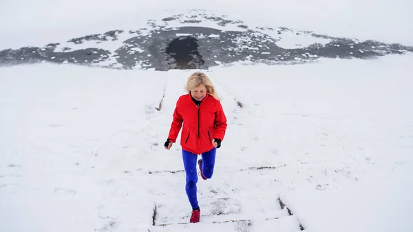 Hoge hoek uitzicht van actieve oudere vrouw buiten in besneeuwde winter, hardlopen. — Stockfoto