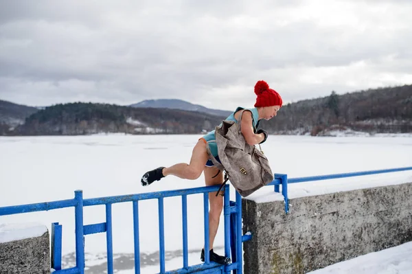 Aktivní seniorka v plavkách přecházející plot venku v zimě, koncepce studené terapie. — Stock fotografie