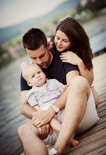 Familie sitzt auf Seebrücke — Stockfoto