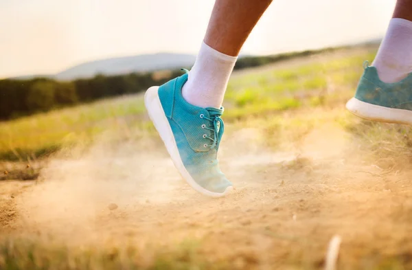 Male feet running on countryside road