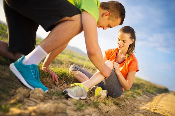 Woman with injured knee getting help — Stock Photo, Image