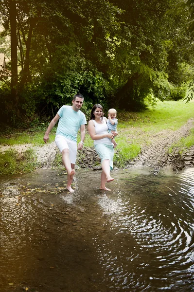 Família feliz salpicando água no rio — Fotografia de Stock