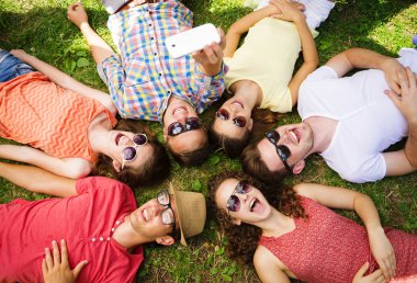 People lying on the grass and taking selfie clipart