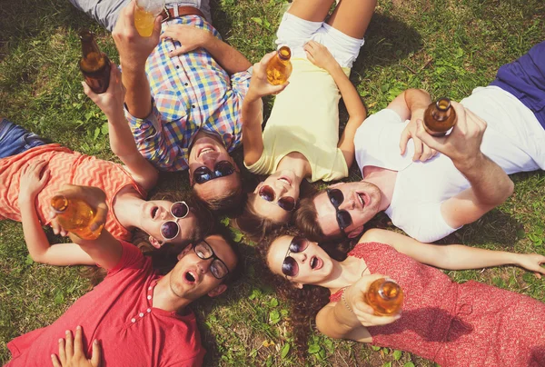 Människor ligger på gräset med drycker — Stockfoto