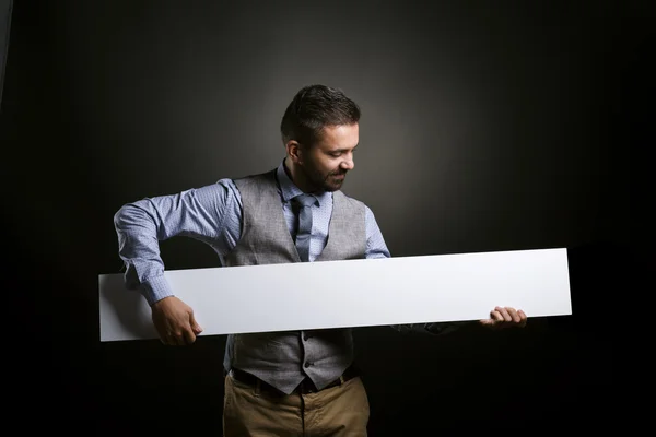 Empresario sosteniendo cartel en blanco — Foto de Stock