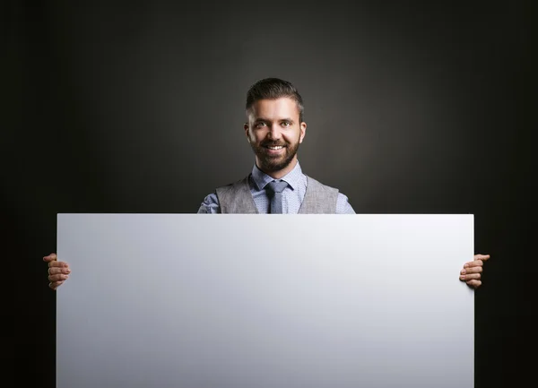 Empresario sosteniendo cartel en blanco — Foto de Stock