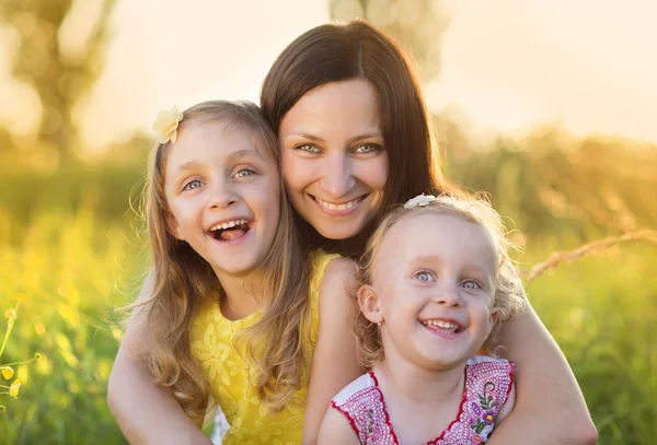 Happy mother with daughters in sunny meadow — Stock Photo, Image