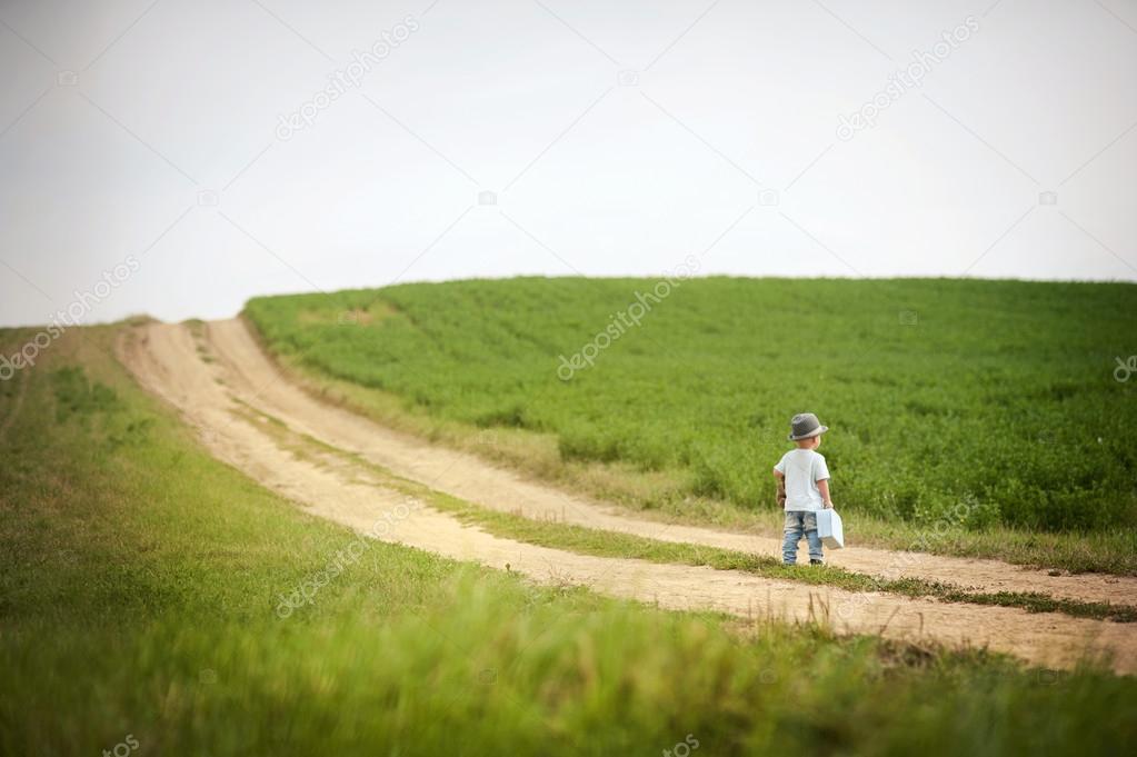 Little boy walking on the footpath in field
