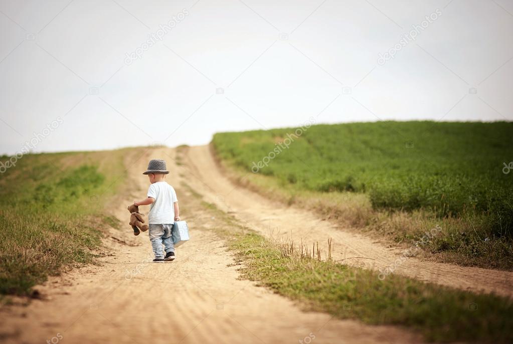 Little boy walking on the footpath in field