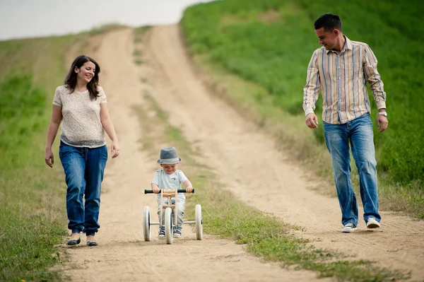 Familia con niño pequeño en triciclo caminando — Foto de Stock