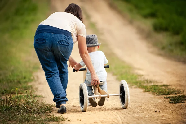 Mother with boy on wooden tricycle — Stock Photo, Image